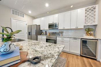 A kitchen with white cabinets and a granite countertop.